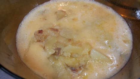 frothy beaten eggs on large bowl mixed with fried potato slices and onion