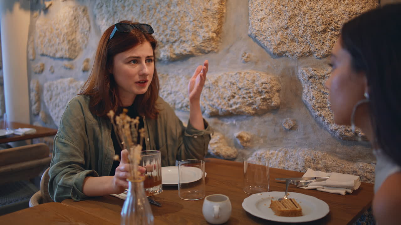 Two women having a conversation over coffee and dessert