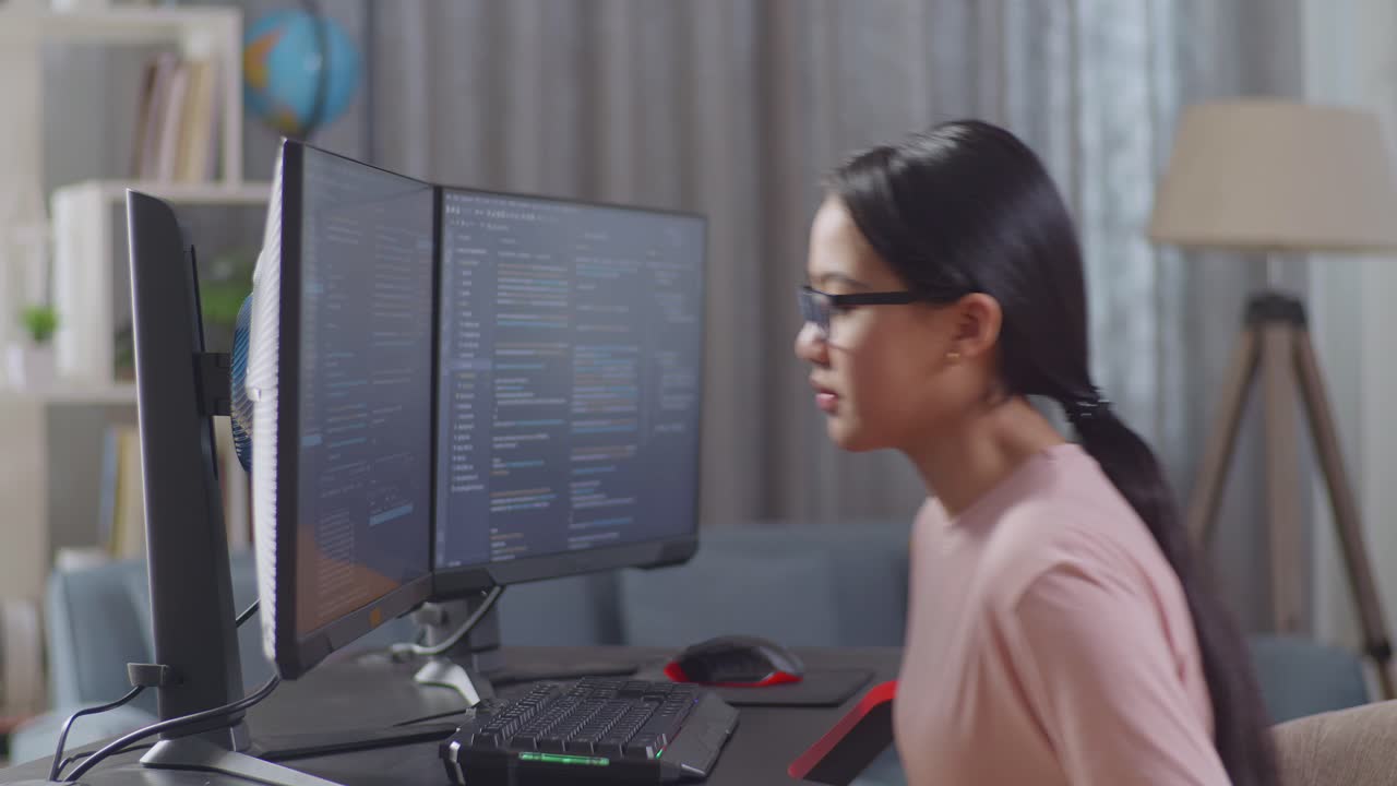 Teenage girl coding on dual monitors