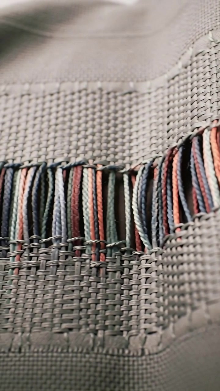 Vertical video: Panning camera showing gray weave sliding in studio exposing seam and color fringe
