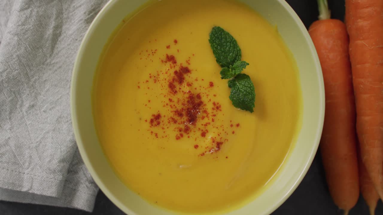 video de sopa de verduras con crema en un cuenco en una mesa gris con zanahorias