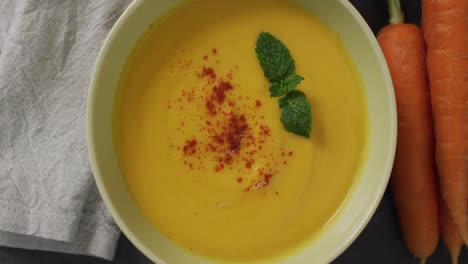 video of cream vegetable soup in bowl on grey table with carrots