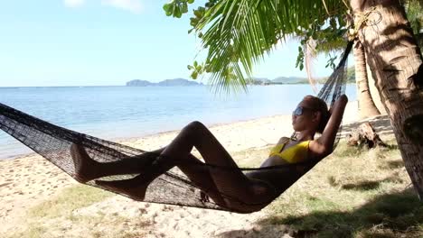 young asian girl, relaxes in a hammock on the beach