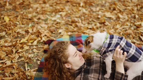 Mujer-Acostada-Sobre-Un-Cuadros-Con-Su-Cachorro-Jack-Russell-Terrier-En-El-Parque-De-Otoño-Y-Divirtiéndose