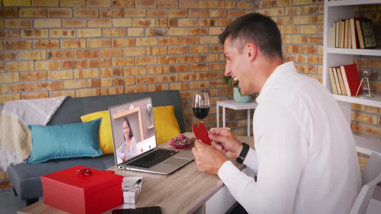 발렌타인 데이트 비디오 통화에서 다양한 커플 노트북 화면에 미소 짓는 남자가 심장을 들고