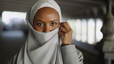 african-american woman covers face with hijab on waterfront