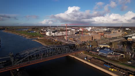 Gran-Puente-Levadizo-De-Acero-Sobre-El-Río-Ijssel-Vista-Aérea-Del-Tránsito-Y-El-Paso-Elevado-De-La-Vía-Del-Tren-Con-El-Lugar-De-Construcción-De-Kade-Zuid-En-El-Barrio-De-Noorderhaven,-Antigua-Zona-Industrial