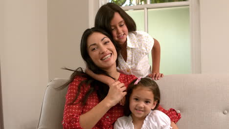 Cheerful-mother-sitting-with-her-daughters-on-the-sofa