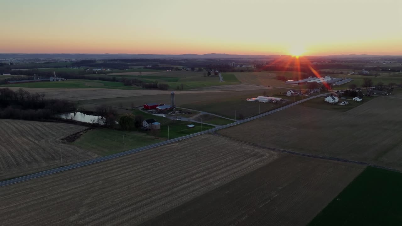 сельский пейзаж сша с дорогами и фермерскими домами во время золотого заката. повышающийся дрон широко расстреливается в сумерках. красивая погода осенью. сельскохозяйственные поля с узором.