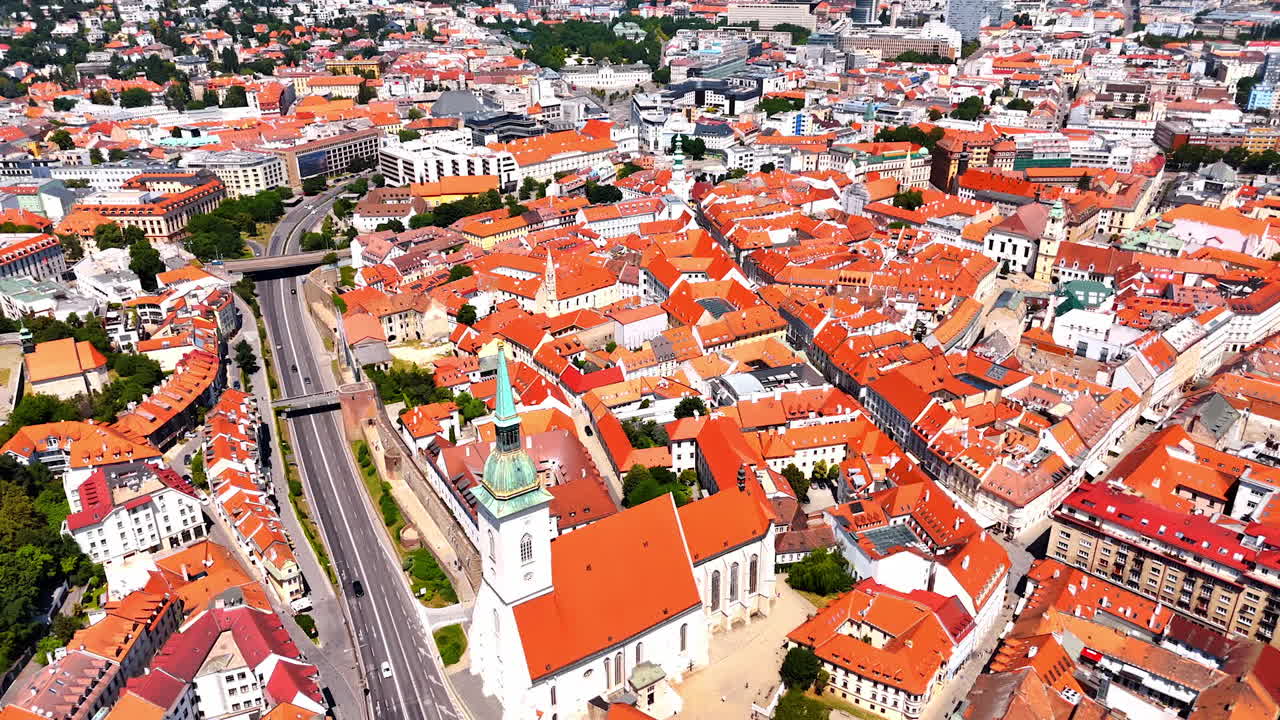 Scenery of bright orange roofs in the old town of Bratislava, Slovakia. Approaching the old church near the road. Aerial perspective