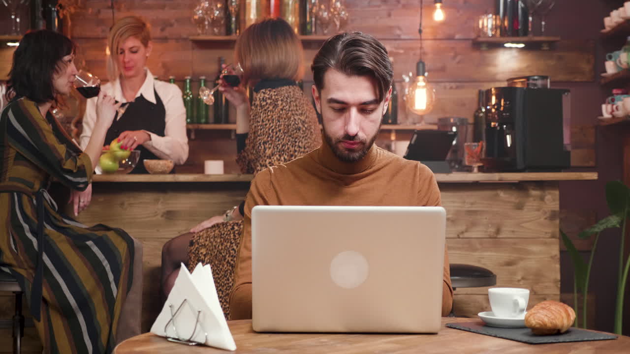 Mand arbejder på bærbar computer på en café
