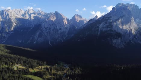 Toma-Aérea-Rotacional-De-Drones-De-4k-De-Un-Hermoso-Valle-En-Los-Dolomitas,-Lleno-De-Pinos-Con-Una-Vista-Excepcional-De-Montañas-Y-Formaciones-Rocosas-En-El-Fondo-En-El-Norte-De-Italia