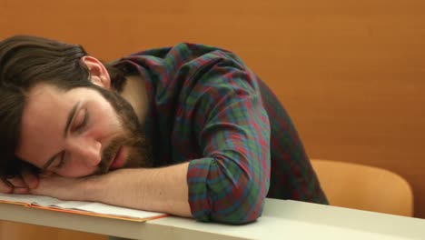 Estudiante-Dormido-Con-La-Cabeza-Apoyada-En-Su-Escritorio