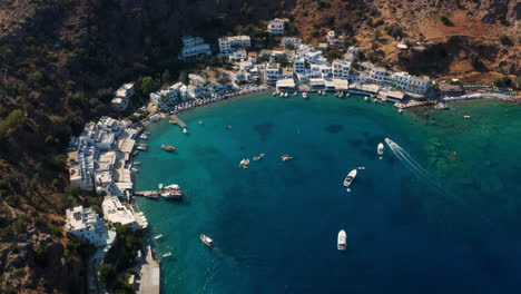 barcos y yates flotando en el mar azul claro cerca de la playa y el pueblo de loutro en creta, grecia