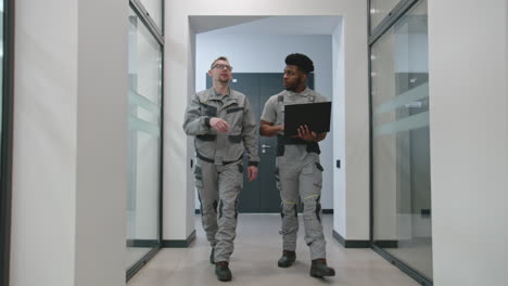 two workers discussing in office corridor