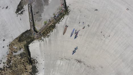drone giratorio por encima de las damas playa galway irlanda como la gente camina barcos currach más cerca de la orilla de las aguas