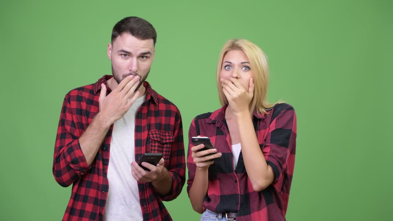 Young couple using phone and looking shocked together