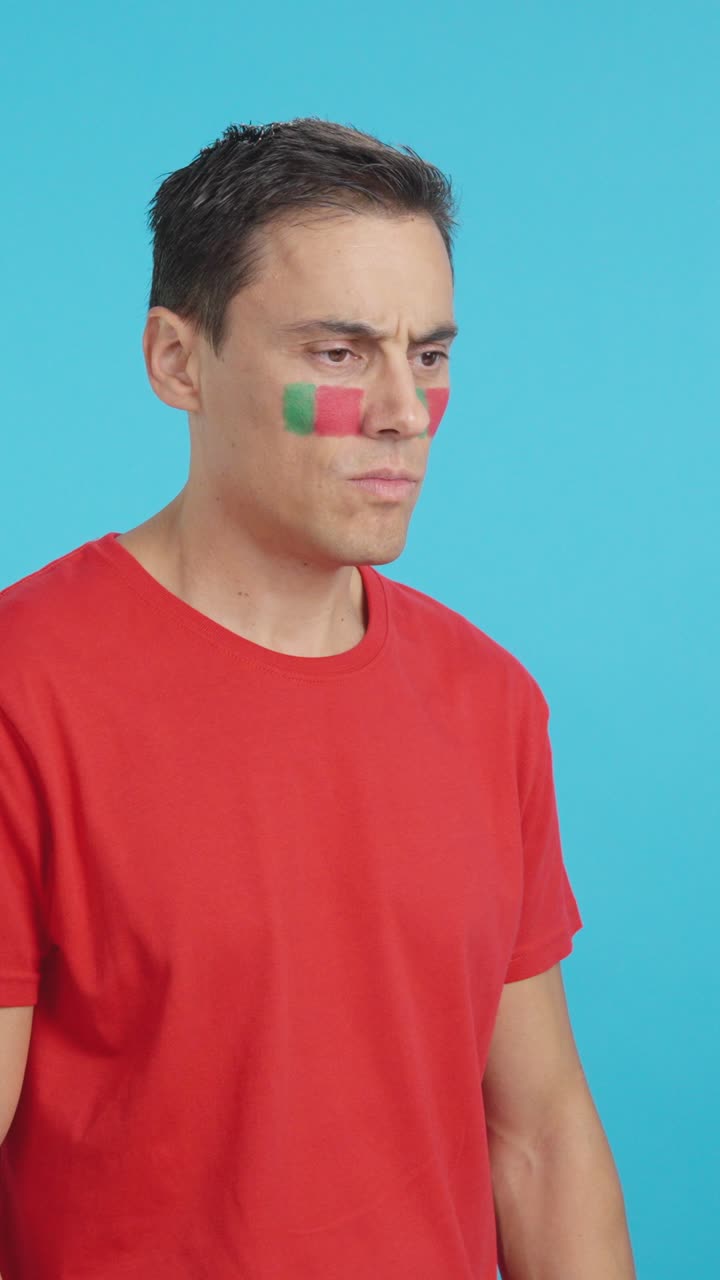 Man with portuguese flag painted looking away with serious expression