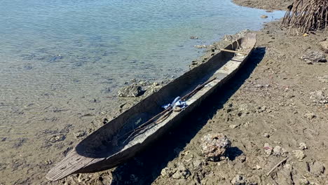 a canoe built from a tree stump in the mud of a river at low tide