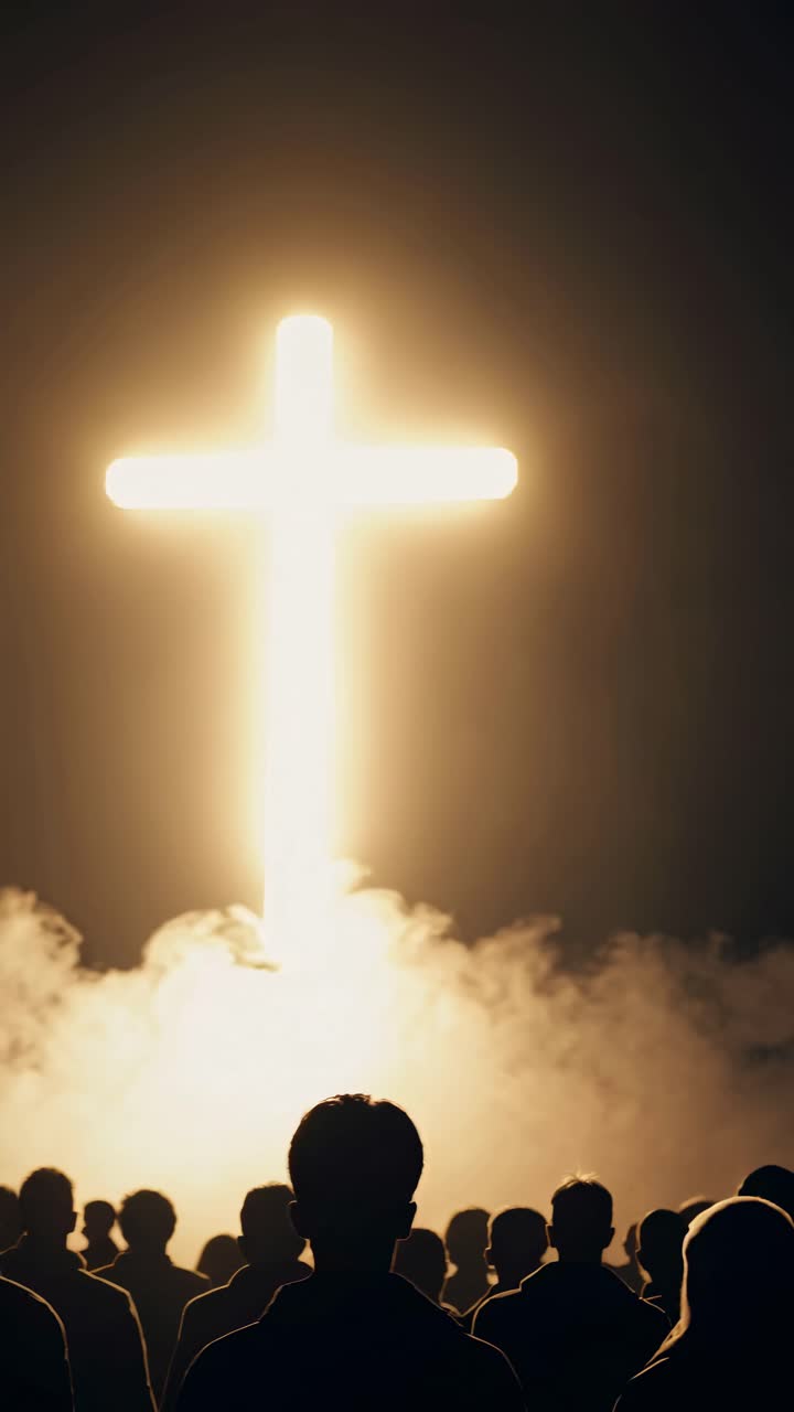 Silhouetted crowd facing a glowing cross with mist, captured from a low angle