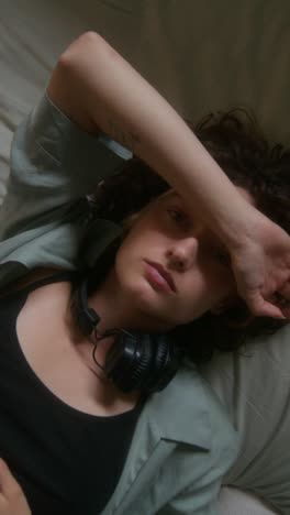 woman resting in bed with headphones