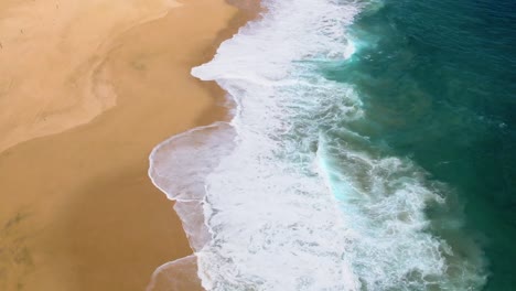 Aerial-drone-shot-of-waves-crashing-into-shoreline