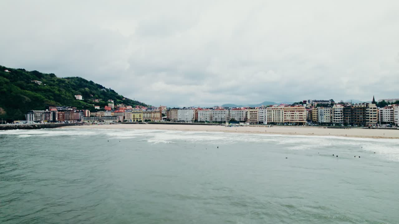 paisaje urbano costero con playa y surfistas