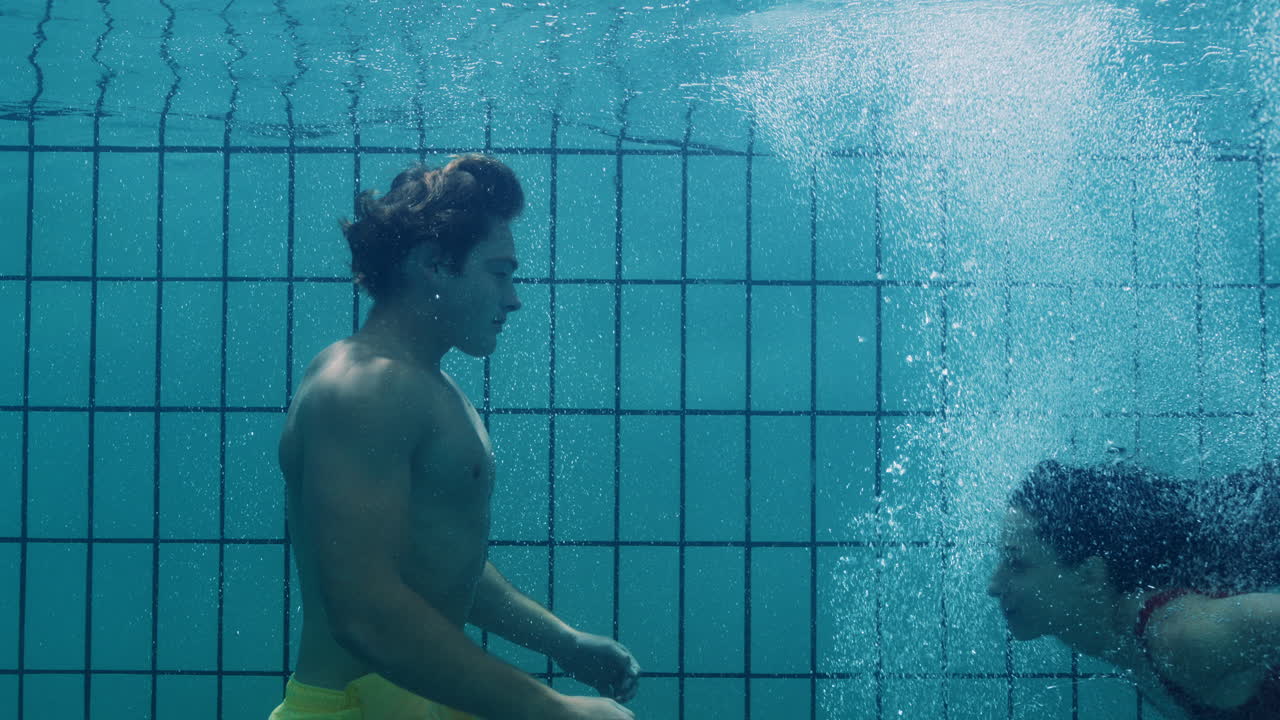 pareja romántica besándose bajo el agua en la piscina jóvenes enamorados disfrutando de un beso íntimo amantes sumergidos en el agua flotando con burbujas en una intimidad apasionada