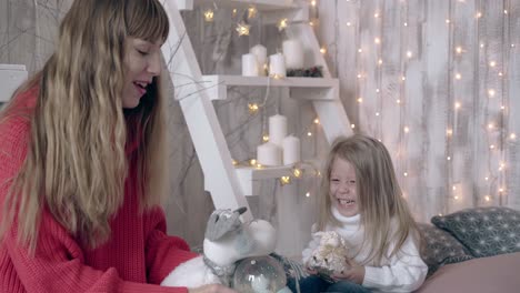 fair-haired-mum-shows-snow-globe-to-smiling-daughter