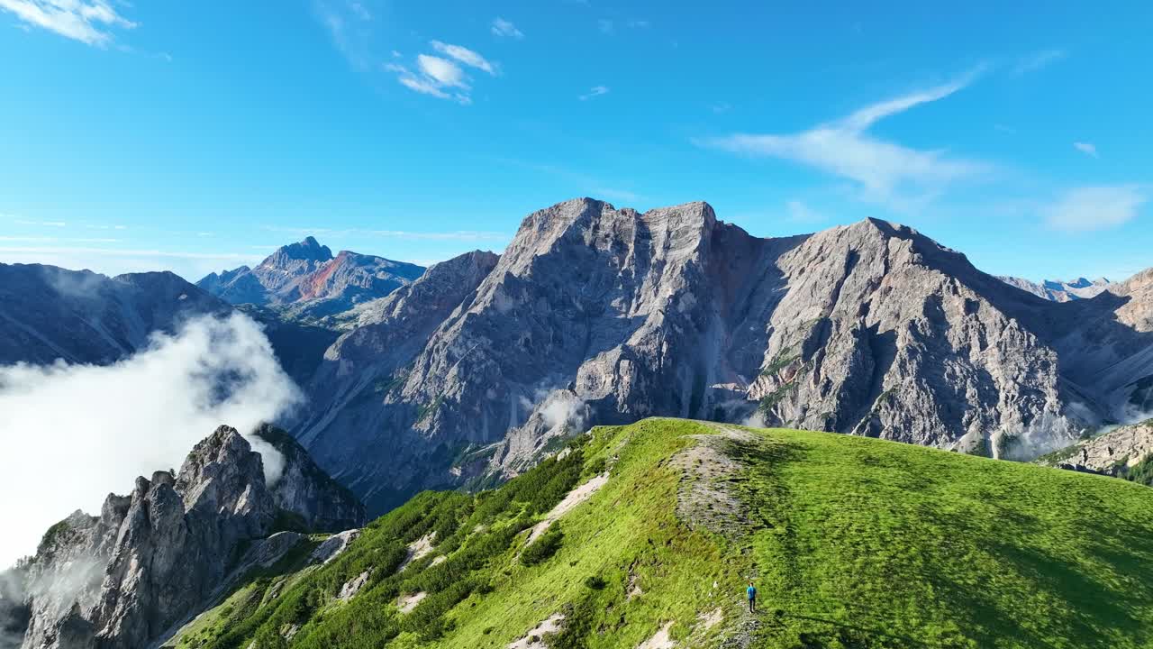 Revealing drone shot of a jagged, rugged mountain peak in Italy's Dolomite mountain range on a sunny summer day
