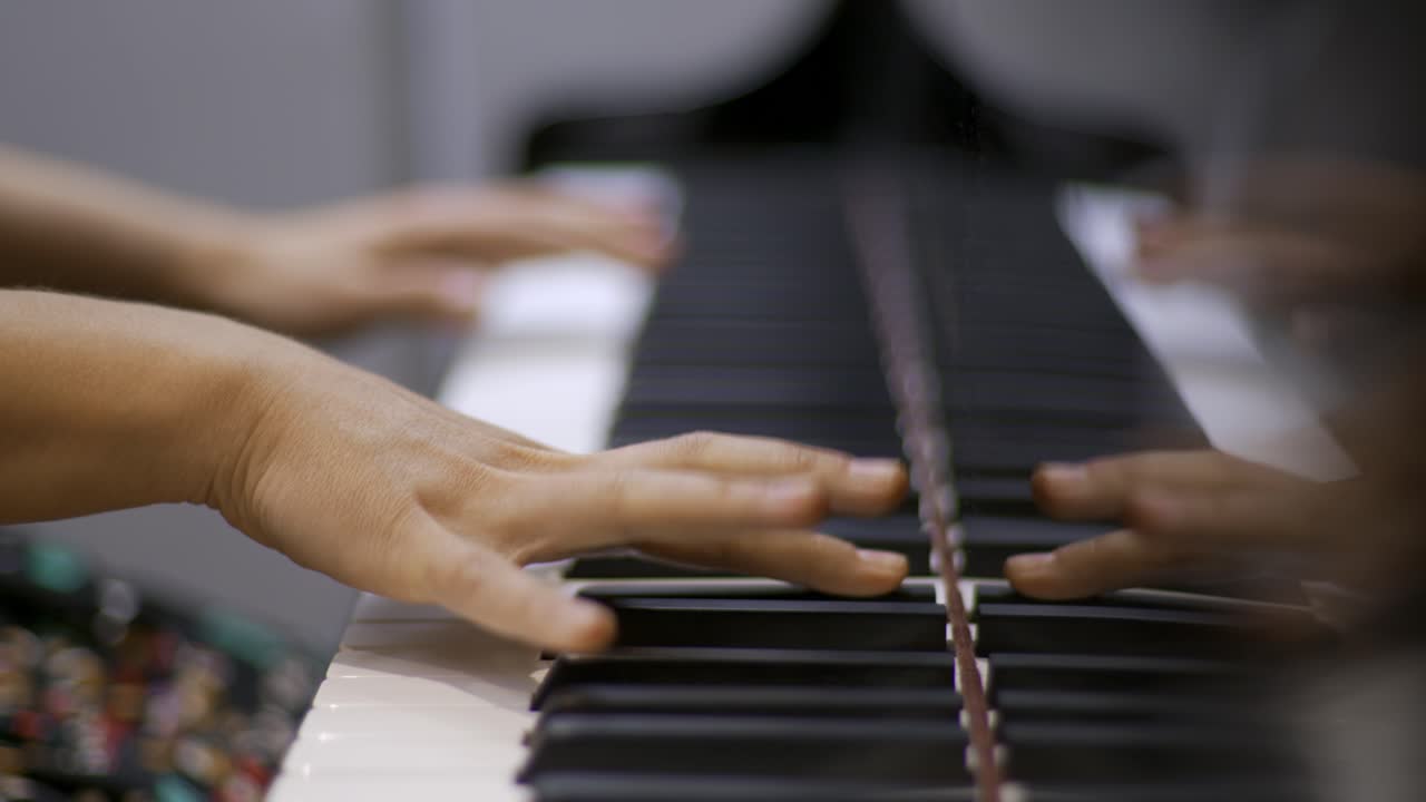 Close up of a professional piano players hands playing and improvising during a recording session with a bright background. Sliding movement reveal. Shallow depth; racking focus. Shot in 4K.