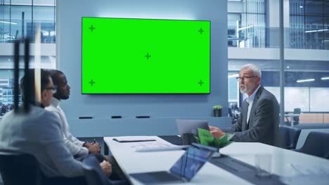 office conference room meeting using video call: diverse team of successful managers, executives talk, use green screen chroma key tv. businesspeople work on strategy for an e-commerce startup