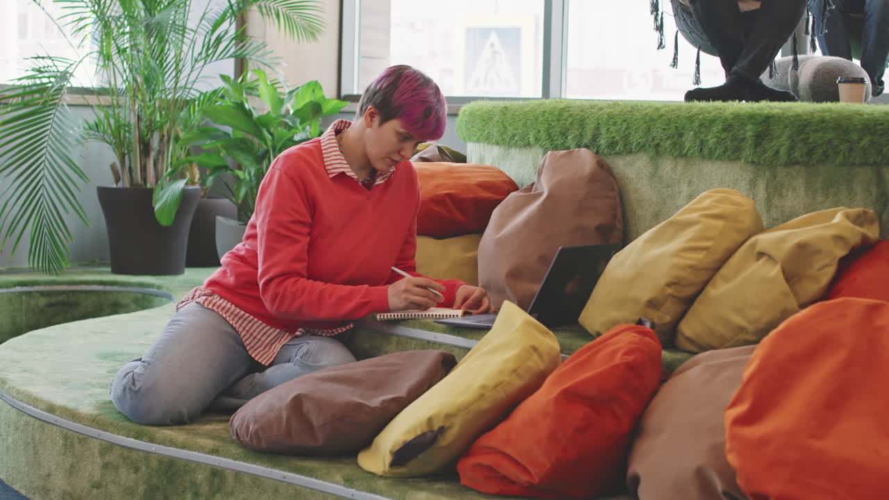Woman Working on Laptop and Making Notes in Coworking Space