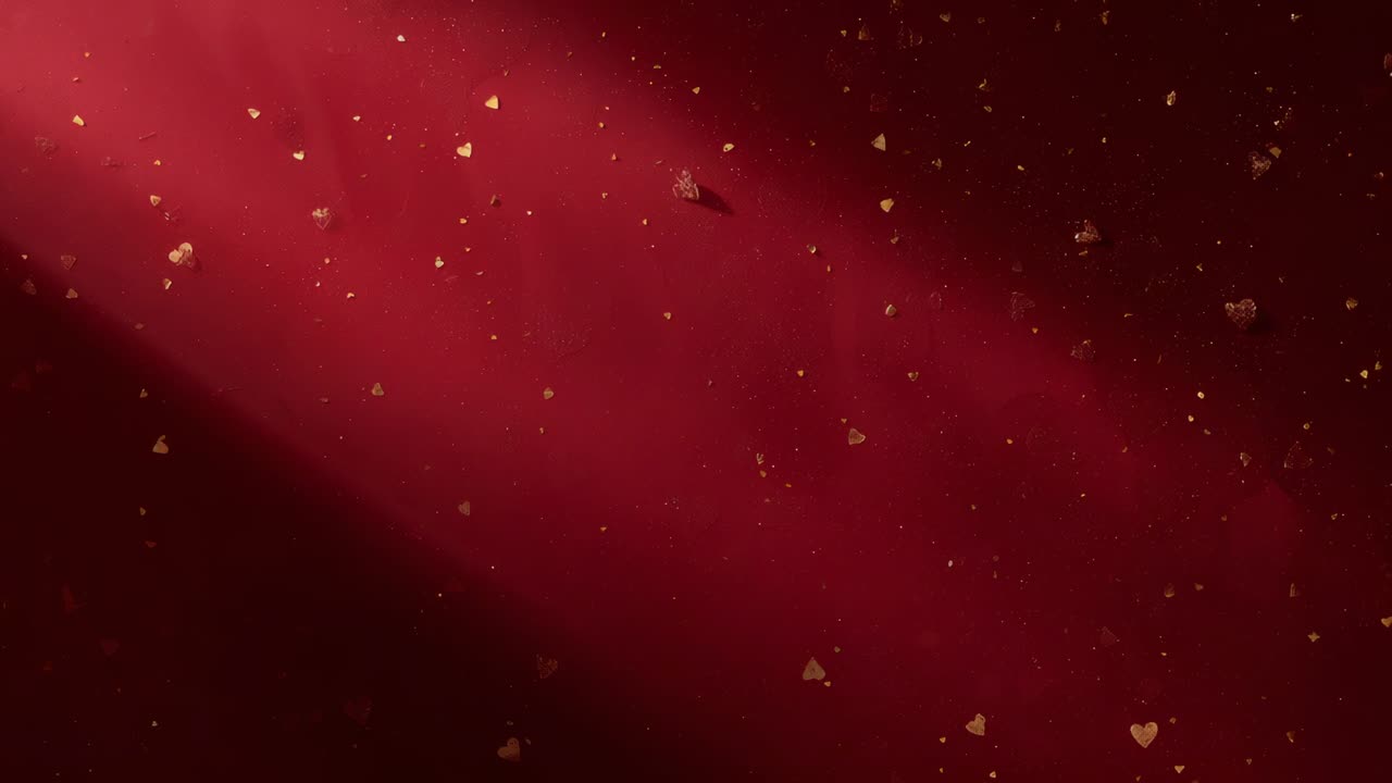 Shifting diagonal sheen sweeping across closeup red fabric, causing gold hearts and flecks drifting