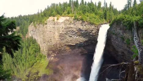turista sentado en el borde del acantilado cerca de una cascada 4k