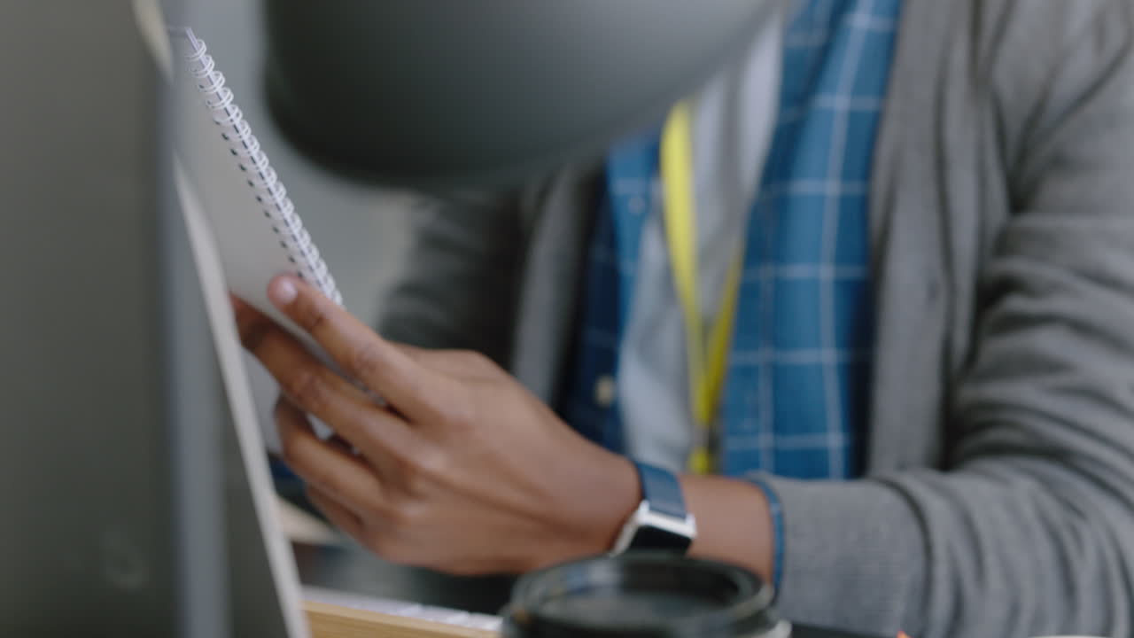 manos cerradas hombre de negocios afroamericano escribiendo notas leyendo documentos corporativos haciendo lluvia de ideas usando la estrategia de planificación por computadora en una empresa moderna