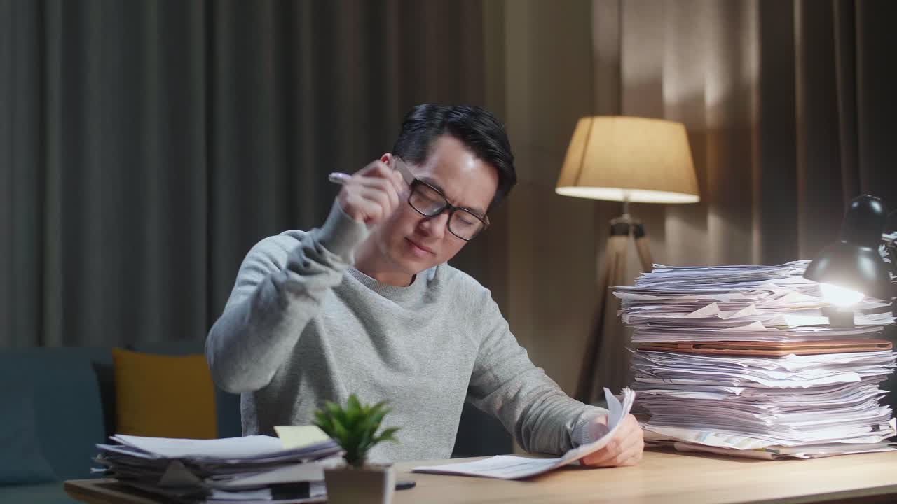 행복한 아시아인 남자가 집에서 문서 작업을 마치고 축하하고 있습니다.