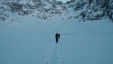 Alpinists-Hiking-Through-Frozen-Lake-in-High-Mountains