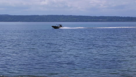 Small,-nondescript-fishing-boat-cruising-past-beach-at-Camano-Island-State-Park,-WA-State