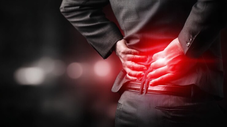 A business professional experiences discomfort in their lower back, depicting the effects of stress and physical strain in a high-pressure work environment