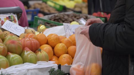 woman picking oranges from a stall of fresh fruits at the local market