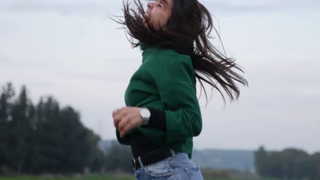 an excited young woman jumps for joy outdoors on a brisk autumn day