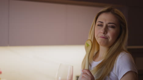 la dama bebe vino tinto y canta cocinando la cena festiva