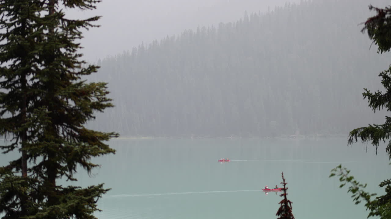 tiro medio de canoas en un lago con montañas humeantes en el fondo en 4k