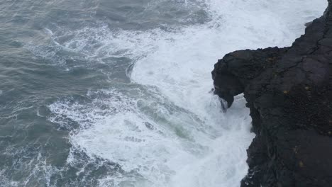 Olas-Espumosas-Rompiendo-En-La-Formación-De-Un-Arco-De-Piedra-Volcánica-En-La-Costa-Cerca-De-La-Ciudad-De-Þorlákshöfn-En-La-Costa-Sur,-Islandia