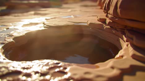 a close-up exploration of natural geological formations featuring water pools reflecting light in an eroded rock landscape