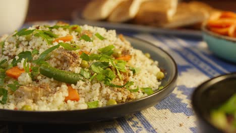 sprinkling pepper on couscous with chicken on table close-up. arabian cuisine. pita and bulgur on background. traditional middle eastern culture. delicious rice with meat. homemade food concept