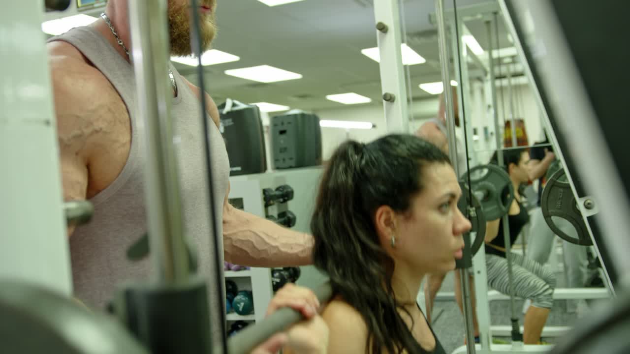 Trainer male correcting fit woman does gym exercises