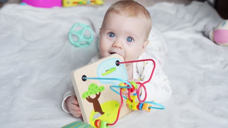 infant girl playing on bed with interactive toy, engaging her senses in a calm indoor space, medium frontal view