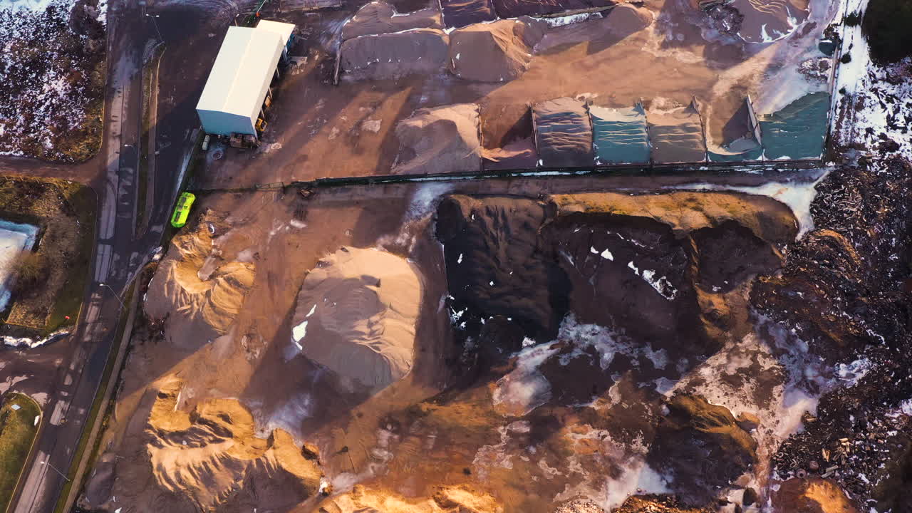 Sand and dirt fill piles for construction in snow covered forest, drone bird's eye view
